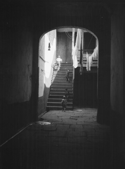 View of a courtyard through an arched passageway, New Orleans, between 1920 and 1926. Creator: Arnold Genthe.