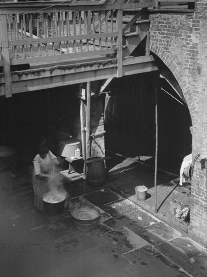 Woman doing laundry in a courtyard, New Orleans, between 1920 and 1926. Creator: Arnold Genthe.