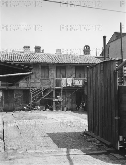 View of two-story dwellings with laundry hanging over balcony railing, New Orleans, c1920-1926. Creator: Arnold Genthe.