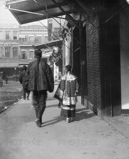 Man and a young girl walking down a sidewalk, Chinatown, San Francisco, between 1896 and 1906. Creator: Arnold Genthe.