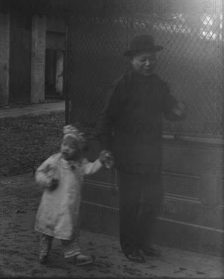 Man and a young child walking down a street, Chinatown, San Francisco, between 1896 and 1906. Creator: Arnold Genthe.