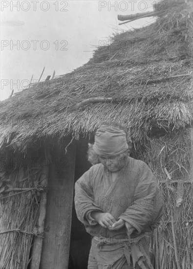 Ainu woman outside a hut, 1908. Creator: Arnold Genthe.