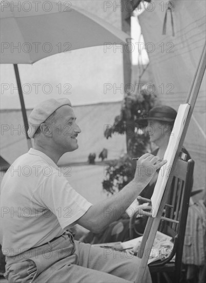 Man seated outdoors painting, East Hampton, Long Island, between 1933 and 1942. Creator: Arnold Genthe.