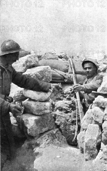 Life in the trenches in Champagne; A lookout 'teased' by the enemy is passed hand grenades, 1917. Creator: Unknown.