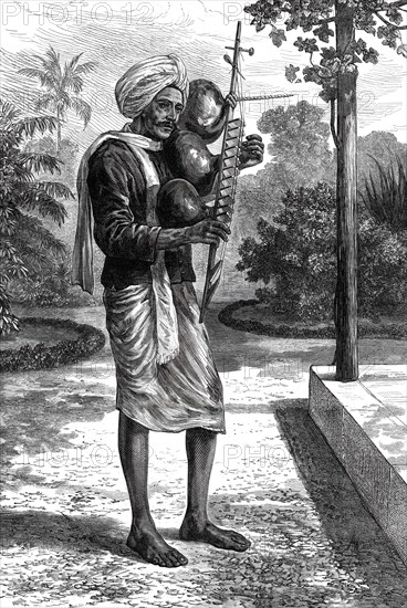 A strolling minstrel at Madras playing the tingadee, 1876. Creator: Unknown.