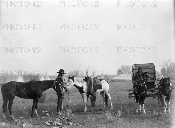 High Medicine Rock, Crow Indian with two horses at left, Her Horse Kills with child in..., c1908. Creator: Edward Sheriff Curtis.