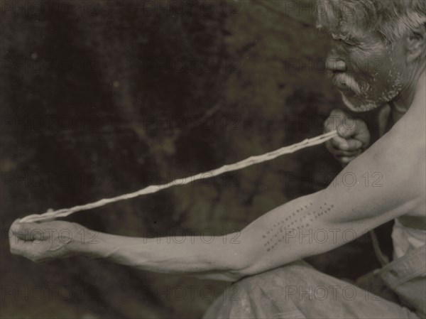 Measuring shell money-Tolowa, c1923. Creator: Edward Sheriff Curtis.