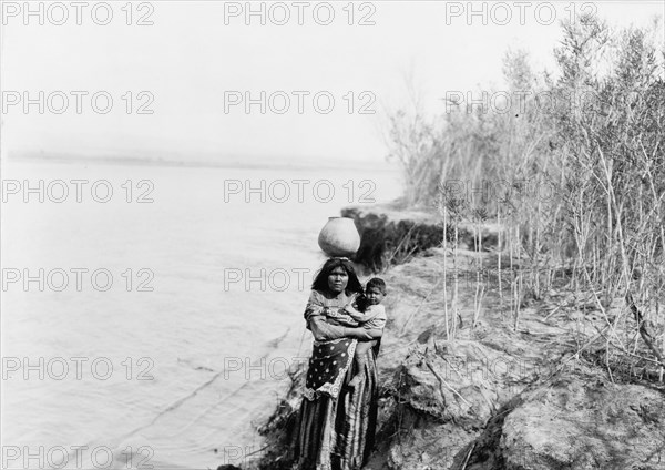 Mohave woman carrying water on her head and holding child, c1903. Creator: Edward Sheriff Curtis.