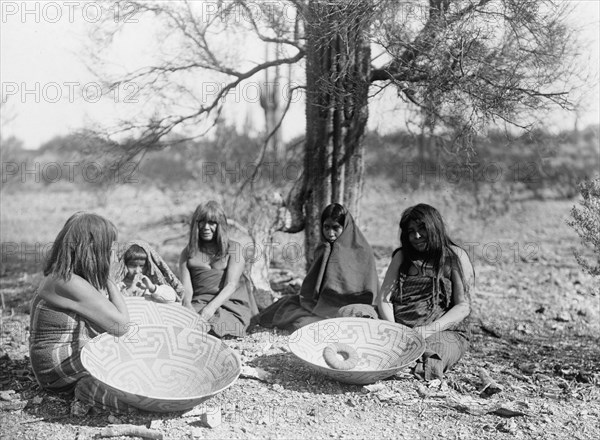 Maricopa group, Arizona. Four women and a child seated on ground with three large basket trays,c1907 Creator: Edward Sheriff Curtis.