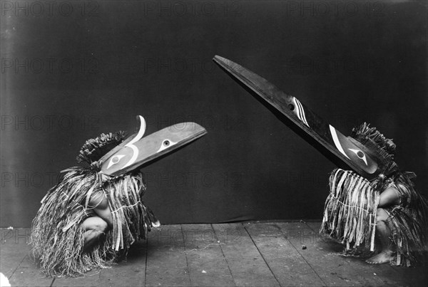 Kotsuis and Hohhug-Nakoaktok, wearing ceremonial dress, with long beaks, on their haunches..., c1914 Creator: Edward Sheriff Curtis.