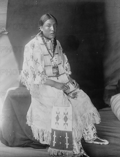 Red Elk Woman, a Sioux girl, full-length portrait, seated, facing right, c1907. Creator: Edward Sheriff Curtis.