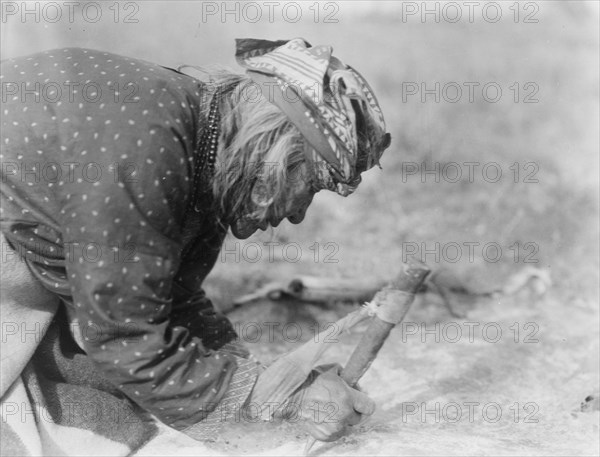 Blackfoot Indian fleshing a hide, c1927. Creator: Edward Sheriff Curtis.