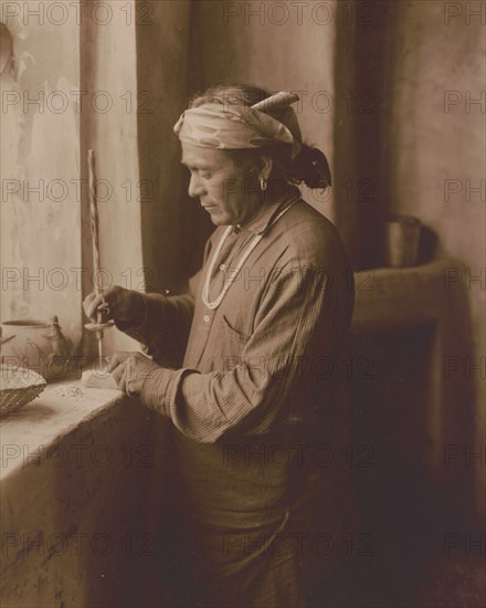 Zuni Indian bead worker drilling holes in beads, c1903. Creator: Edward Sheriff Curtis.