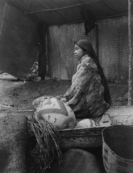 A Skokomish Indian chief's daughter, half-length portrait, seated on canoe, facing left, c1913. Creator: Edward Sheriff Curtis.