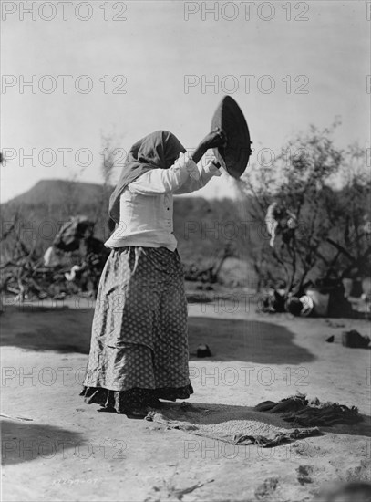 Papago cleaning wheat (Winnowing wheat), c1907. Creator: Edward Sheriff Curtis.