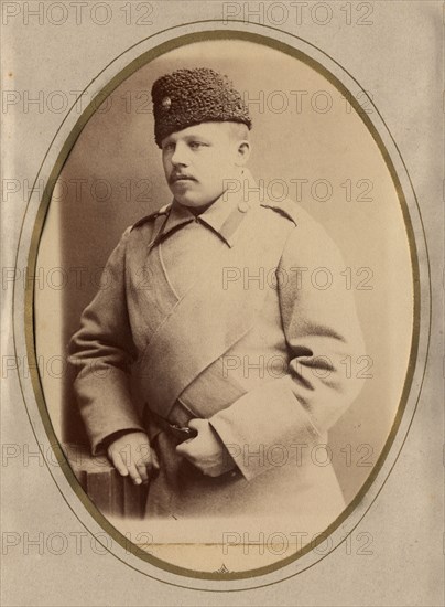 A young man in a fireman's uniform (overcoat and hat), late 19th cent - early 20th cent Creator: Shnee.