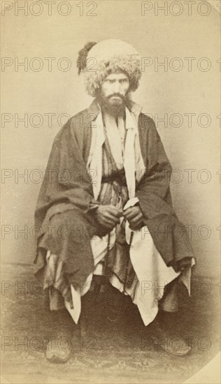 Full-length portrait of man, seated, facing front, between 1870 and 1886. Creator: Unknown.