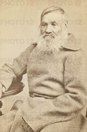 Three-quarter length portrait of an elderly convict, facing slightly left, between 1880 and 1886. Creator: Unknown.