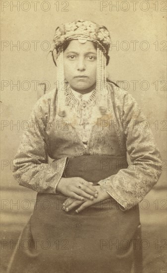 Three-quarters length portrait of a woman, seated, facing front, between 1870 and 1886. Creator: Unknown.