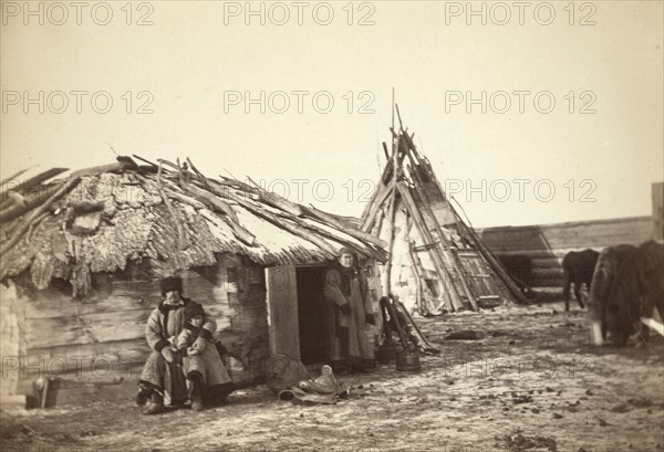Tatar couple with a small boy in front of their home, between 1885 and 1886. Creator: Unknown.