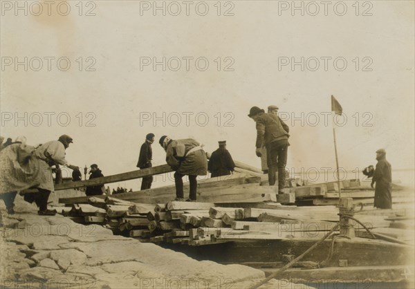 Japanese removing timbers from lighters at Chemulpo for erection of runways, c1904. Creator: Robert Lee Dunn.