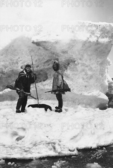 Eskimo with another man in winter scene, between c1900 and 1927. Creator: Lomen Brothers.
