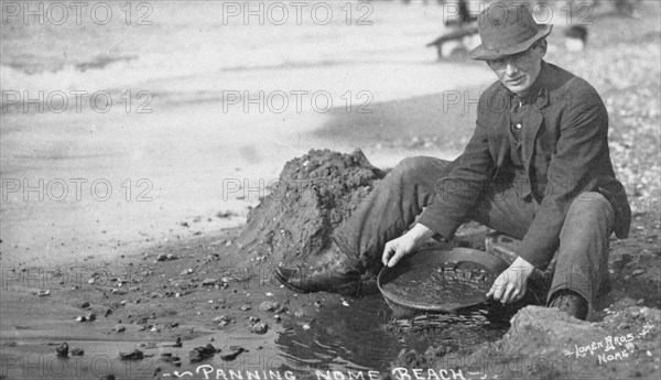 Man panning gold on Nome Beach, between c1900 and c1930. Creator: Lomen Brothers.