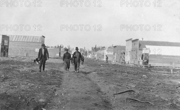 Three men walking down a dirt road, through town, between c1900 and 1916. Creator: Unknown.