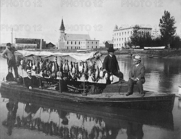 Marshall Erwin in front of a boat containing a kill of ducks, between c1900 and 1927. Creator: Unknown.