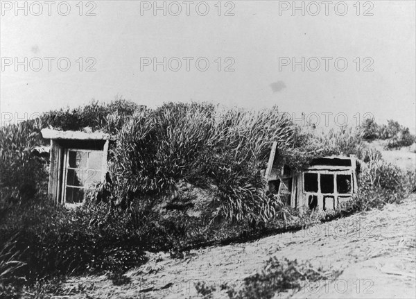 An Aleut house, which is a hole in the earth covered with a framework of driftwood..., c1900-c1930. Creator: Unknown.