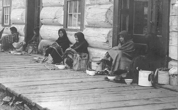 Indians sitting with backs to wall selling berries, between c1900 and c1930. Creator: Unknown.