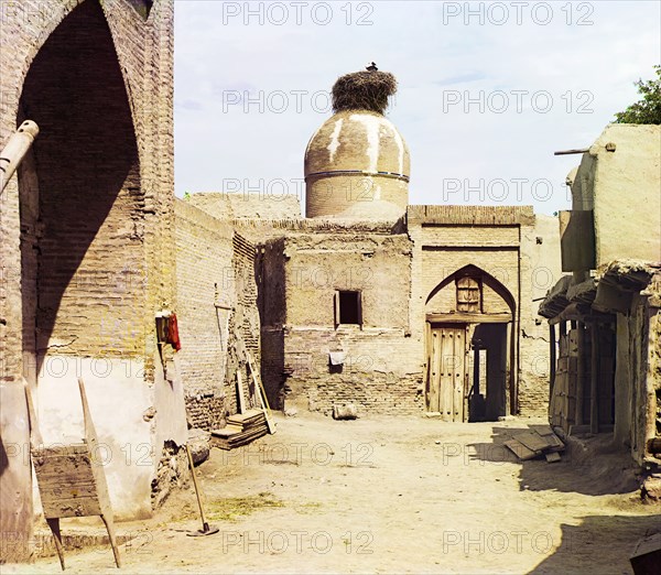 View of a courtyard, adobe buildings, and a bird's nest atop a dome, between 1905 and 1915. Creator: Sergey Mikhaylovich Prokudin-Gorsky.