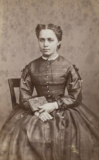 Business card, studio portrait of woman holding a photo album. (c1880s) Creator: Karolina Christianson.