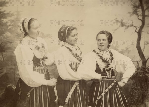 Three young women dressed in costumes from Leksand, Dalarna, 1886-1920. Creator: Helene Edlund.