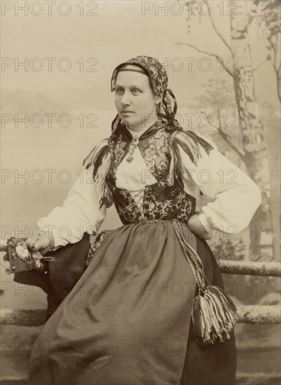 A young woman poses in a folk costume, 1890-1920. Creator: Helene Edlund.