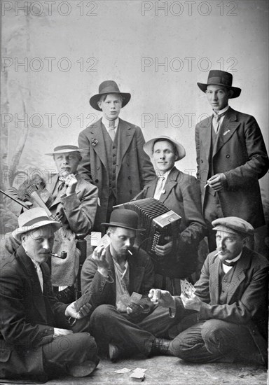 Group photo of men with musical instruments and playing cards, 1915.  Creator: Unknown.