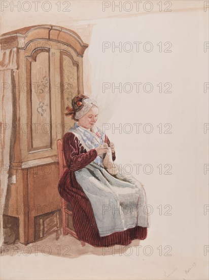 Apparel - Handicraft woman in full figure sitting in front of a cupboard. (c1900s). Creator: AJG Virgin.