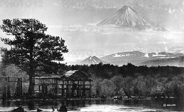 Booths on the river bank against the backdrop of Klyuchevsky volcano, 1922-1923. Creator: Rene Malaise.