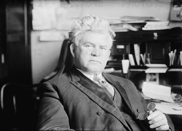 H.T. Rainey, holding bifocals, at desk, 1911. Creator: Bain News Service.