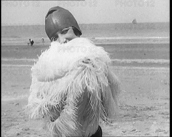 Female Civilian Wearing a Swimsuit Holding a Feathered Parasol at the Beach, 1920. Creator: British Pathe Ltd.