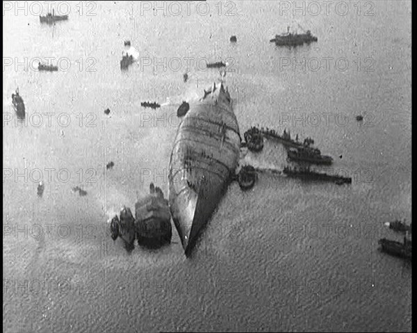 A Capsized Italian Ship at Sea Being Approached by Smaller Vessels, 1921. Creator: British Pathe Ltd.