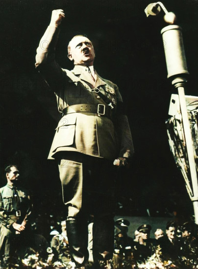 Adolf Hitler addressing a Nazi rally at Nuremberg, Germany, 1930s. The Nazi Party held annual political rallies at Nuremberg from 1927 until 1938. After the Nazis claimed power in 1933 the rallies became massive state propaganda events. Hitler's deputy, Rudolf Hess, is in the bottom left of the picture. (Colorised black and white print).