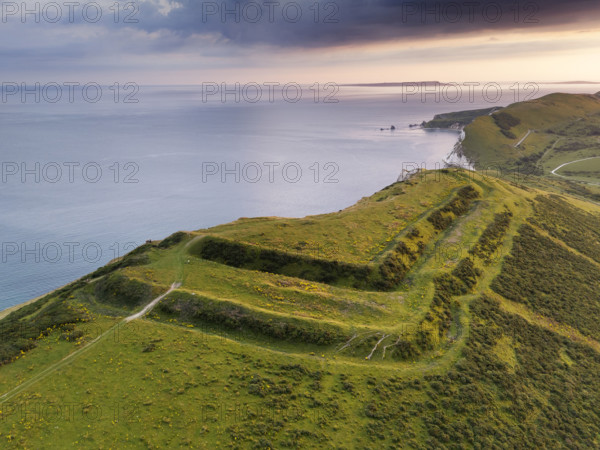 Flower's Barrow, East Lulworth, Dorset, 2024. Oblique aerial view of the hillfort from the north-east, showing how approximately a third of it has been lost to long-term coastal erosion. Drone photography.