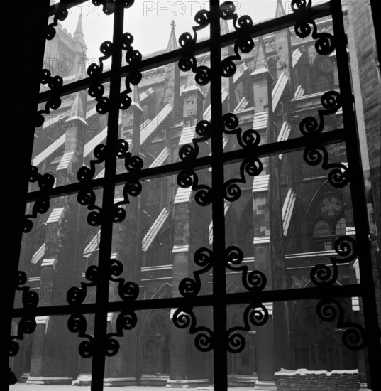 Looking through a wrought iron decorative window grille towards the south facade of the nave of Westminster Abbey, London, 1946-1999.