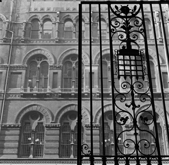 Looking up past the ornate iron gates of Westminster Palace Gardens to the facade of the Army and Navy Stores on Artillery Row, London, 1965-1975.