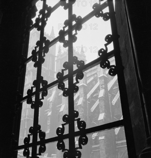 Looking through a wrought iron decorative window grille towards the south facade of the Westminster Abbey's nave, London, 1947-1957.