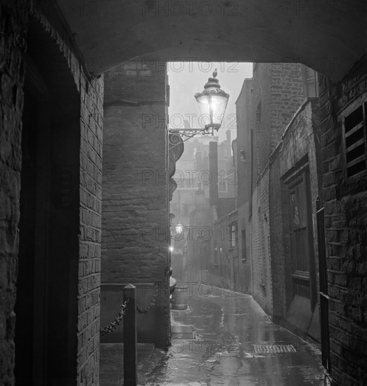 A dimly lit alley in London's theatre land off St Martin's Lane, early 1960s. Image featured in London Observed by John Gay, published June 1964.