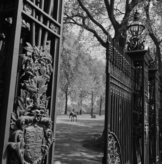 A view through one of the five pairs of elaborate cast iron gates at Queen's Gate, which leads into Hyde Park from Kensington Gore to the south of the park, 1955-1965.