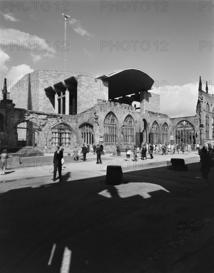 A view of people exploring the ruins of the Cathedral Church of St Michael with the new Coventry Cathedral in the background, 1962. The Cathedral Church of St Michael in Coventry was badly damaged by bombing in 1940 and the new cathedral in the background was built between the mid-1950s to 1962 and consecrated on 25th May 1962.