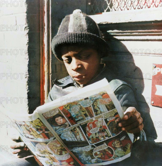 Washington, D.C. Negro youth reading a funny paper on a door step in the Southwest section. (Colorised black and white print).